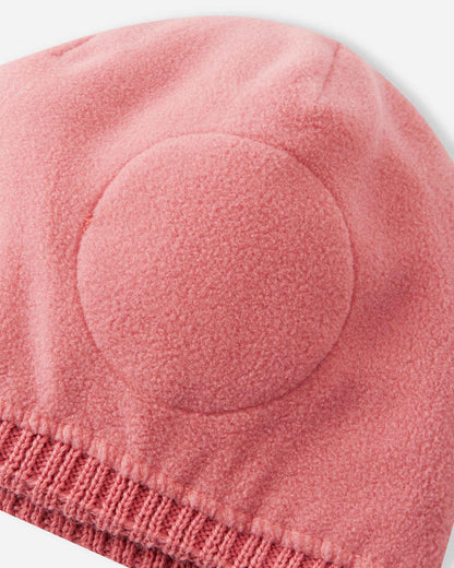 Interior close-up of the Reima Kalotti kids' winter beanie in rose blush, displaying the warm inner fleece lining and the built-in circular windproof earpieces designed to protect against cold winter winds.