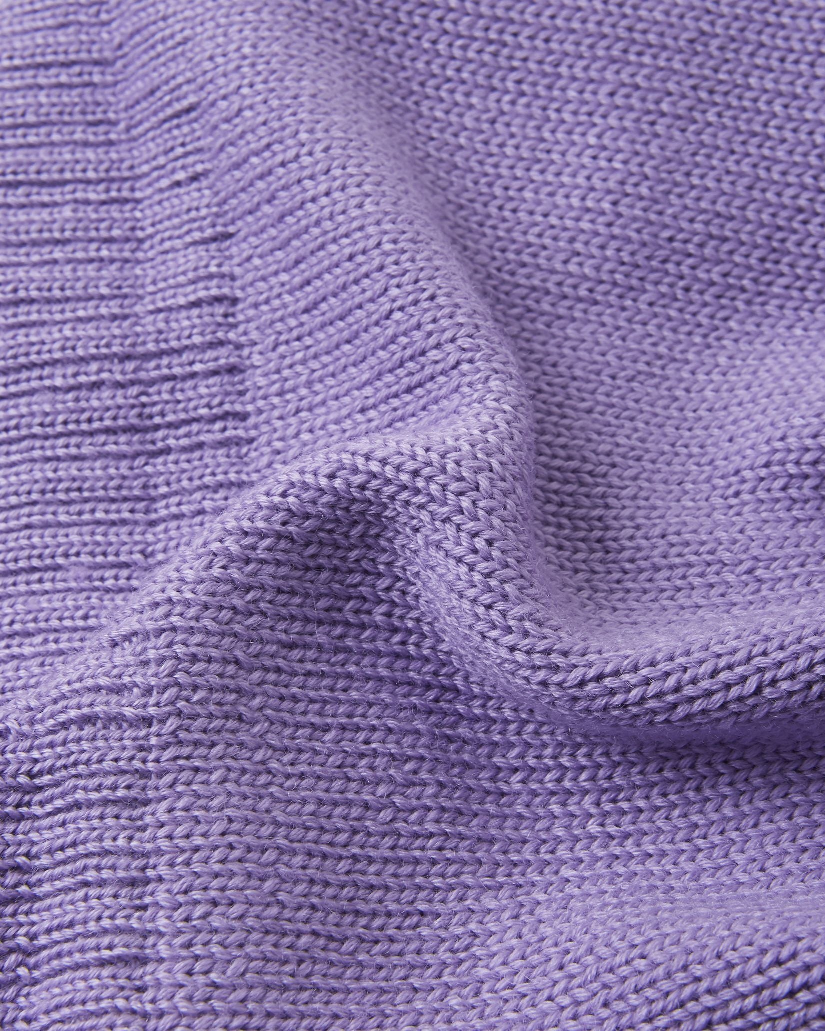Macro close-up of the premium knitted merino wool texture on the blooming lilac Reima Kalotti kids' beanie, demonstrating the soft, breathable, and temperature-regulating winter yarn.