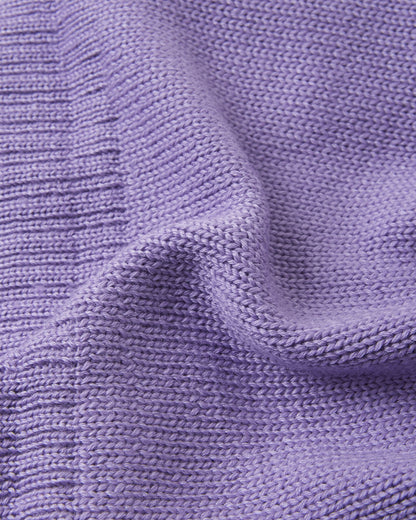 Macro close-up of the premium knitted merino wool texture on the blooming lilac Reima Kalotti kids' beanie, demonstrating the soft, breathable, and temperature-regulating winter yarn.
