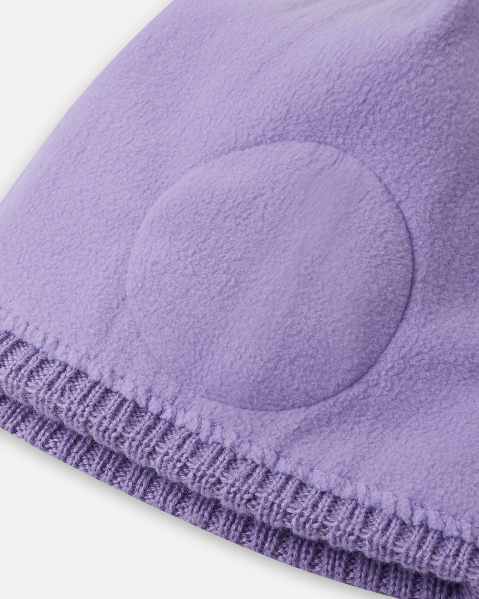 Close-up inside detail of the blooming lilac Reima Kalotti kids' wool beanie, showing the built-in circular windproof earpieces specifically designed to protect little ears from harsh winter winds and frost.