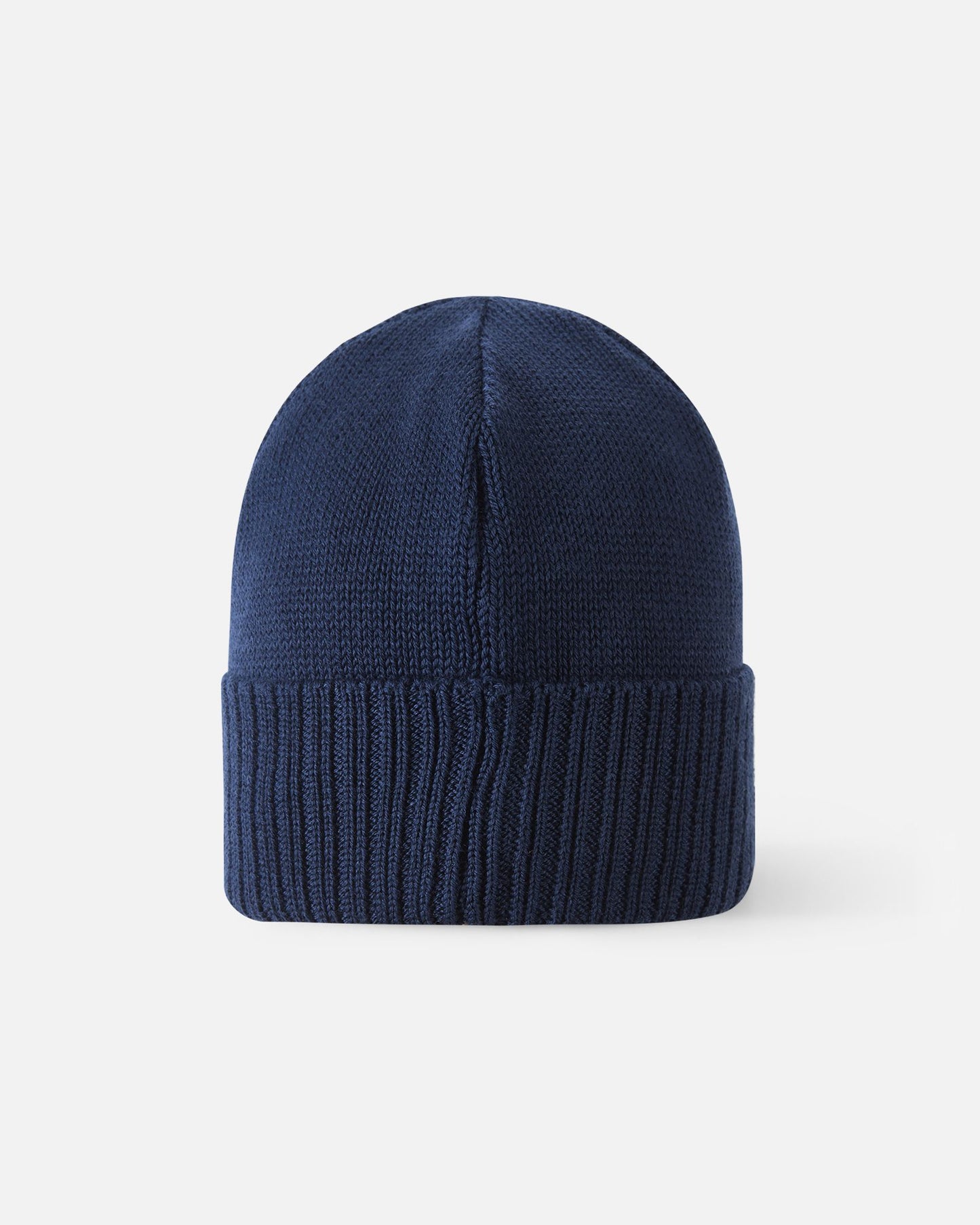 Angled side view of the navy blue Reima Kalotti kids' merino wool beanie hat, highlighting the small black Reima logo tag on the ribbed brim.