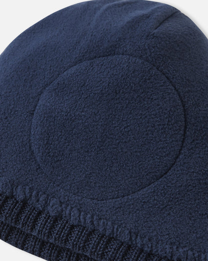 Close-up inside detail of the navy blue Reima Kalotti kids' wool beanie, showing the soft inner lining and the built-in circular windproof earpieces designed for extra winter protection.