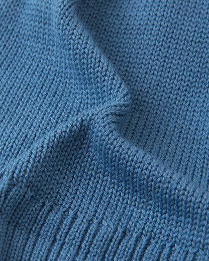 Macro close-up of the premium knitted merino wool texture on the ocean blue Reima Kalotti kids' beanie, demonstrating the soft, breathable, and temperature-regulating winter yarn.