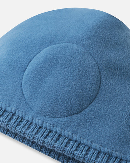 Close-up inside detail of the ocean blue Reima Kalotti kids' wool beanie, showing the soft inner lining and the built-in circular windproof earpieces designed for extra winter protection.