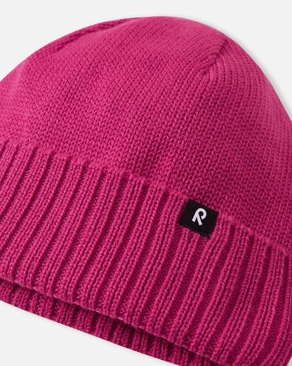 Macro close-up of the premium knitted merino wool texture on the rosy berry Reima Kalotti kids' beanie, demonstrating the soft, breathable, and temperature-regulating winter yarn.