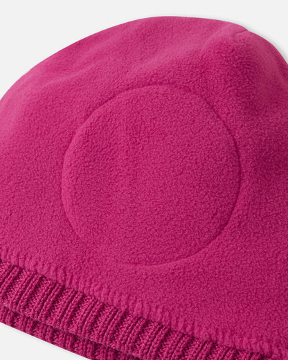 Close-up inside detail of the rosy berry Reima Kalotti kids' wool beanie, showing the soft inner lining and the built-in circular windproof earpieces designed to protect little ears from harsh winter winds.