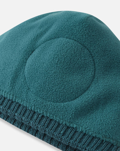 Interior view of the dark teal Reima Kalotti kids beanie, showcasing the merino wool knit and the soft, circular thermal fleece lining designed to provide extra wind protection and warmth for children's ears during outdoor winter activities.