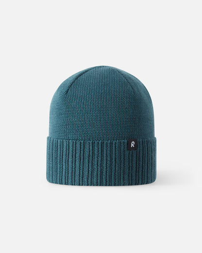 Full front profile of the Reima Kalotti kids winter beanie in a deep dark teal color, featuring a classic dome shape, temperature-regulating merino wool construction, and a wide ribbed cuff for optimal cold-weather insulation.