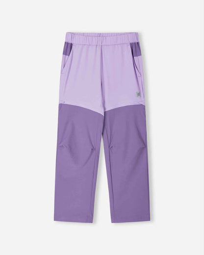 Front view of the Reima Kaveris kids' convertible hiking pants in blooming lilac, featuring a stylish two-tone purple design with darker reinforced lower legs and hidden zippers to seamlessly convert into summer shorts.