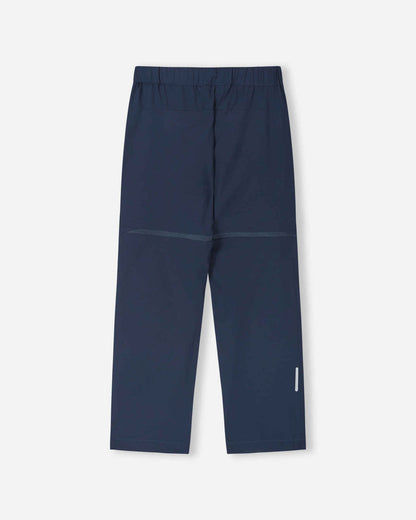 Back view of the navy blue Reima Kaveris kids' hiking pants, showcasing the durable, stretch outdoor fabric, articulated knee seams, and a reflective safety detail on the lower right leg for trail visibility.
