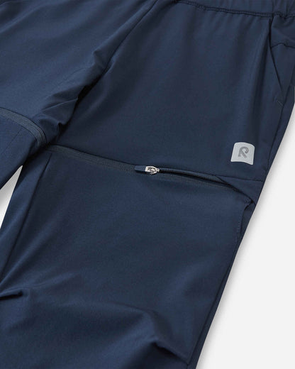 Macro close-up of the hidden zipper detail on the Reima Kaveris kids' navy blue convertible pants, demonstrating the high-quality, easy-to-use hardware designed for quickly detaching the lower pant legs.