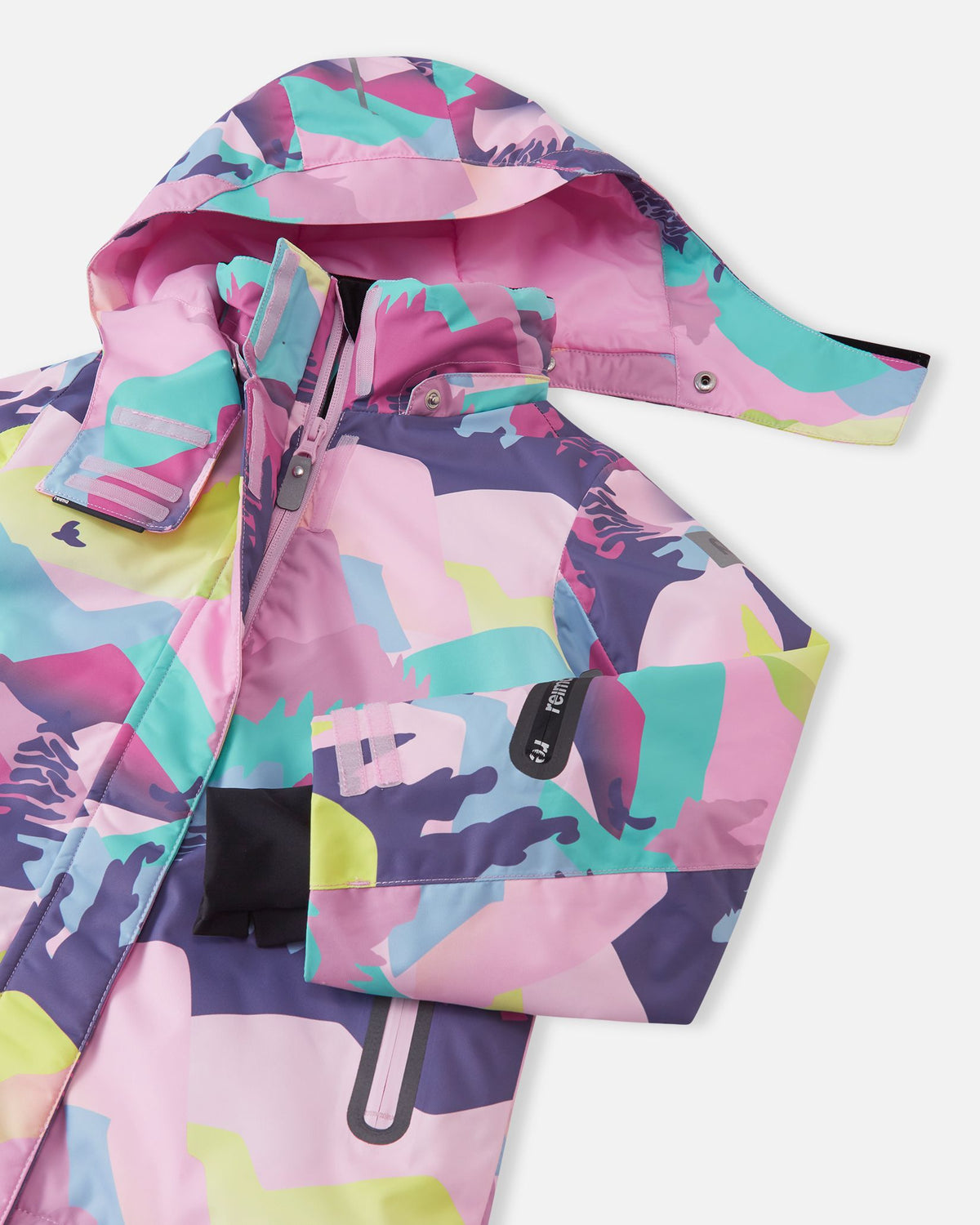 Close-up of the upper chest and collar on the Reima Kiiruna girls' ski jacket in grey pink, detailing the snap buttons for the detachable hood, the main protective zipper, and the left sleeve ski pass pocket.