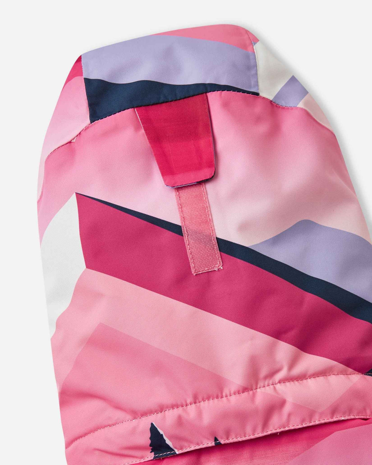 Close-up of the hook-and-loop velcro adjustment strap on the back of the soft coral Reima Kiiruna girls' ski jacket hood, engineered to easily customize the fit over a winter beanie or ski helmet.