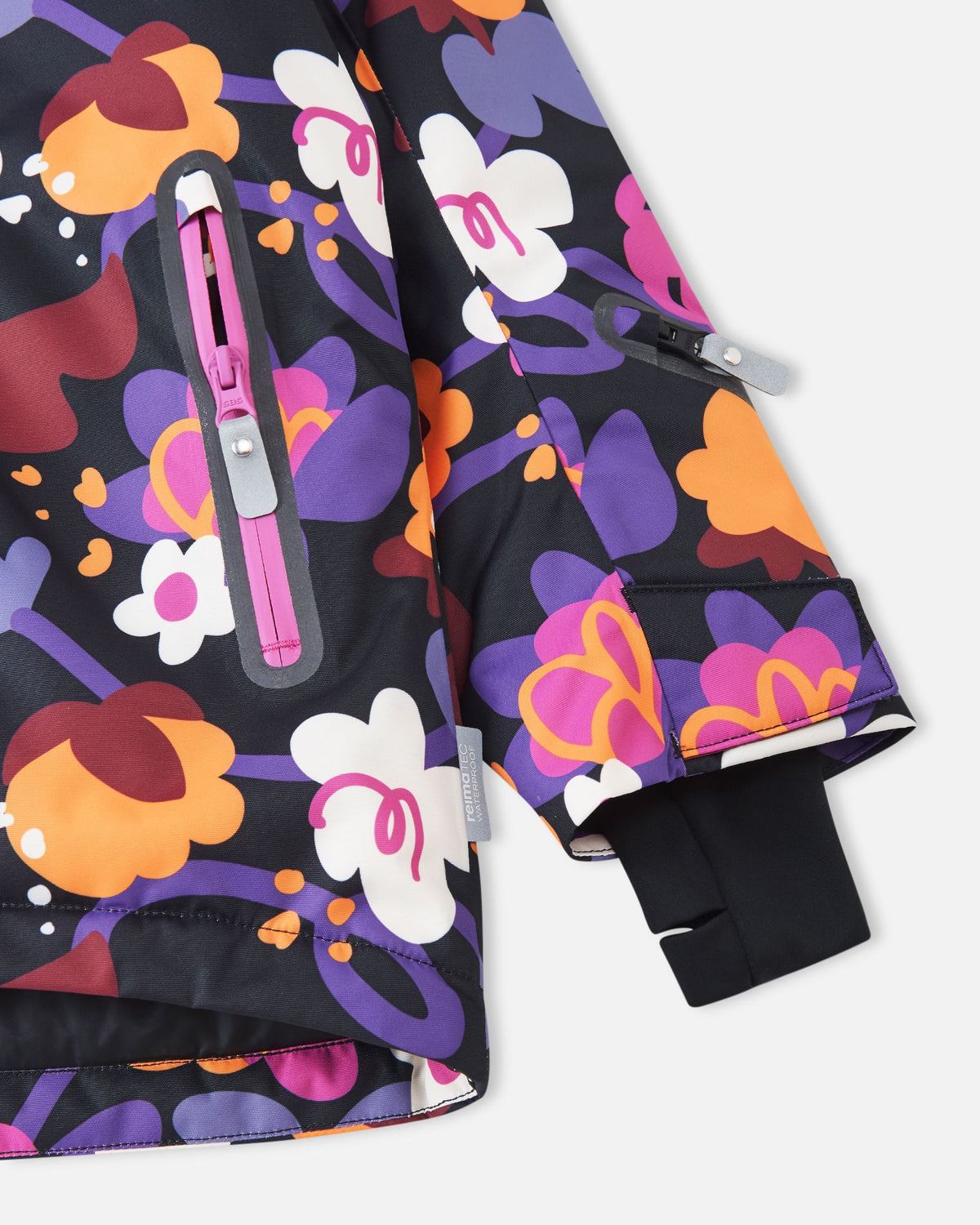 Close-up of the sleeve on the Reima Kiiruna girls' ski jacket, showing the adjustable Velcro outer cuff, black Lycra inner cuff with thumbhole, zippered ski pass pocket, and the Reimatec waterproof authenticity tag.