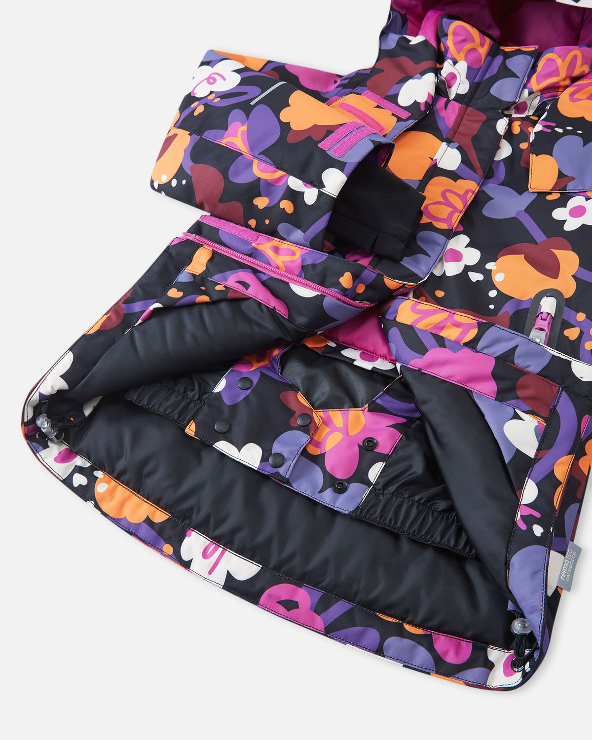 Interior view of the Reima Kiiruna girls' ski jacket, revealing the smooth inner lining and the built-in snap-button snow lock powder skirt designed to keep snow out during winter sports.