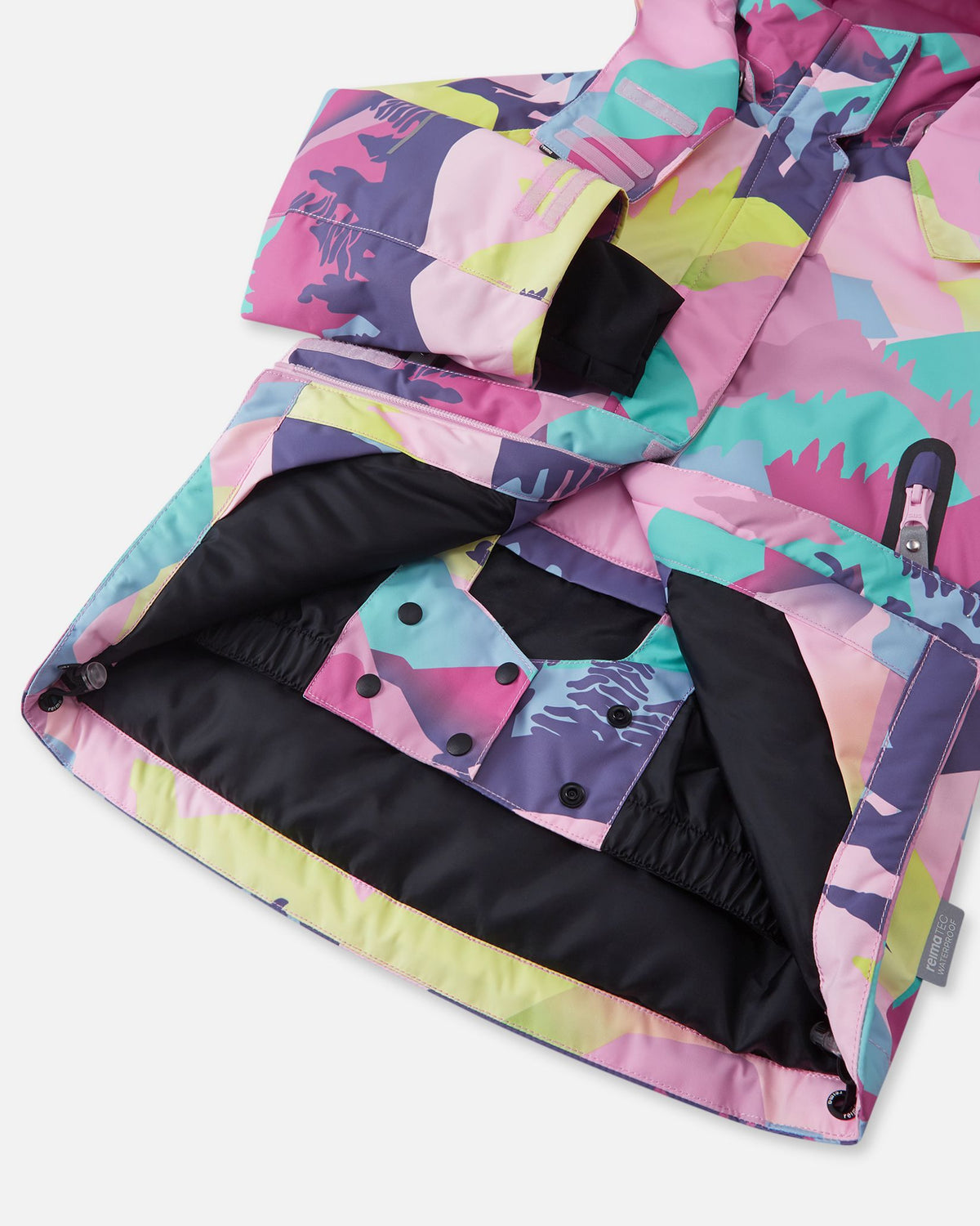 Interior view of the Reima Kiiruna girls' ski jacket, revealing the smooth black lining and the built-in snap-button snow lock powder skirt designed to keep snow out during alpine skiing and snowboarding.