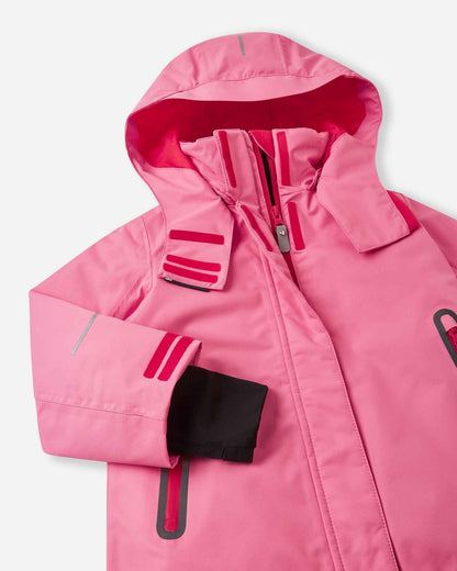 Angled upper-torso detail of the solid soft coral Reima Kiiruna girls' snow jacket, showing the tall fleece-lined collar, durable main zipper with a protective storm flap, and functional chest pocket design.