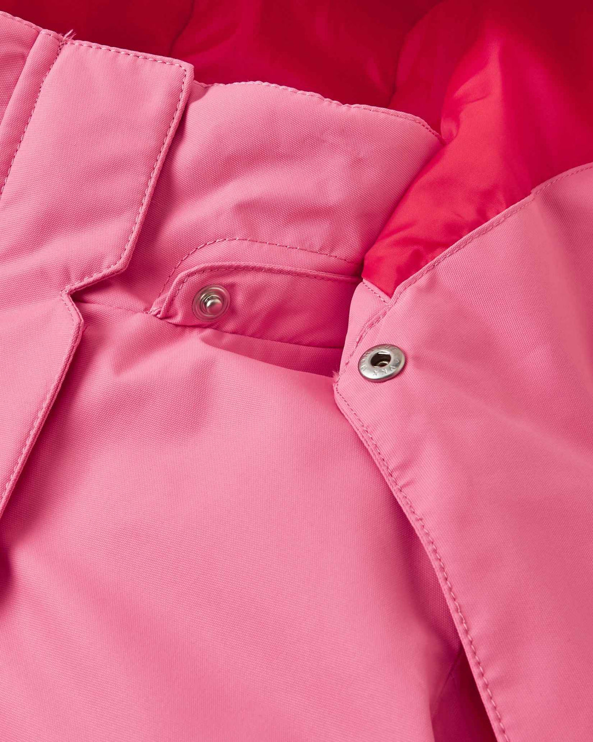 Detailed close-up of the tear-away metallic safety snaps connecting the hood to the collar of the solid soft coral Reima Kiiruna girls' winter coat, ensuring a quick release if snagged during active play.