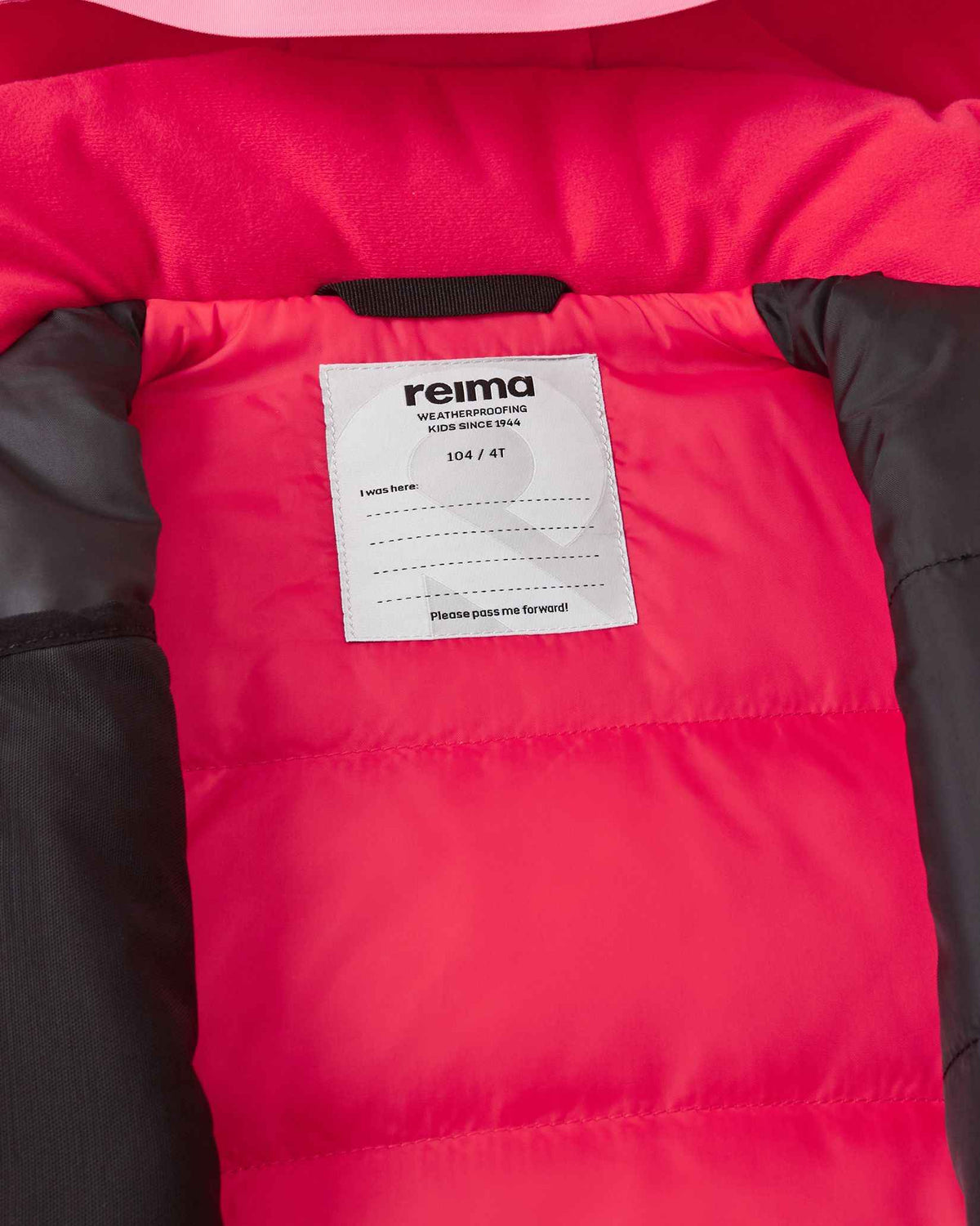 Inside collar view of the soft coral Reima Kiiruna kids' ski apparel, displaying the cozy pink fleece lining, Reima weatherproofing certification badge, and a customizable inner name tag for school or ski camp.