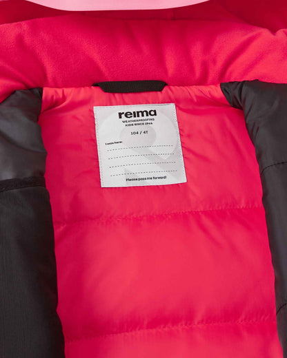 Inside collar view of the soft coral Reima Kiiruna kids' ski apparel, displaying the cozy pink fleece lining, Reima weatherproofing certification badge, and a customizable inner name tag for school or ski camp.