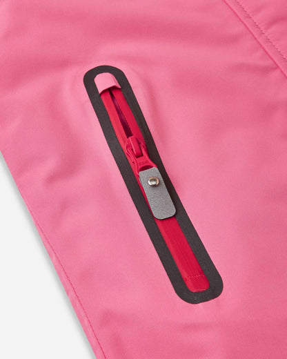 Close-up of the vertical zippered pocket on the solid soft coral Reima Kiiruna kids' snow jacket, featuring a water-resistant zipper track and a reflective pull tab for easy access with bulky ski gloves.