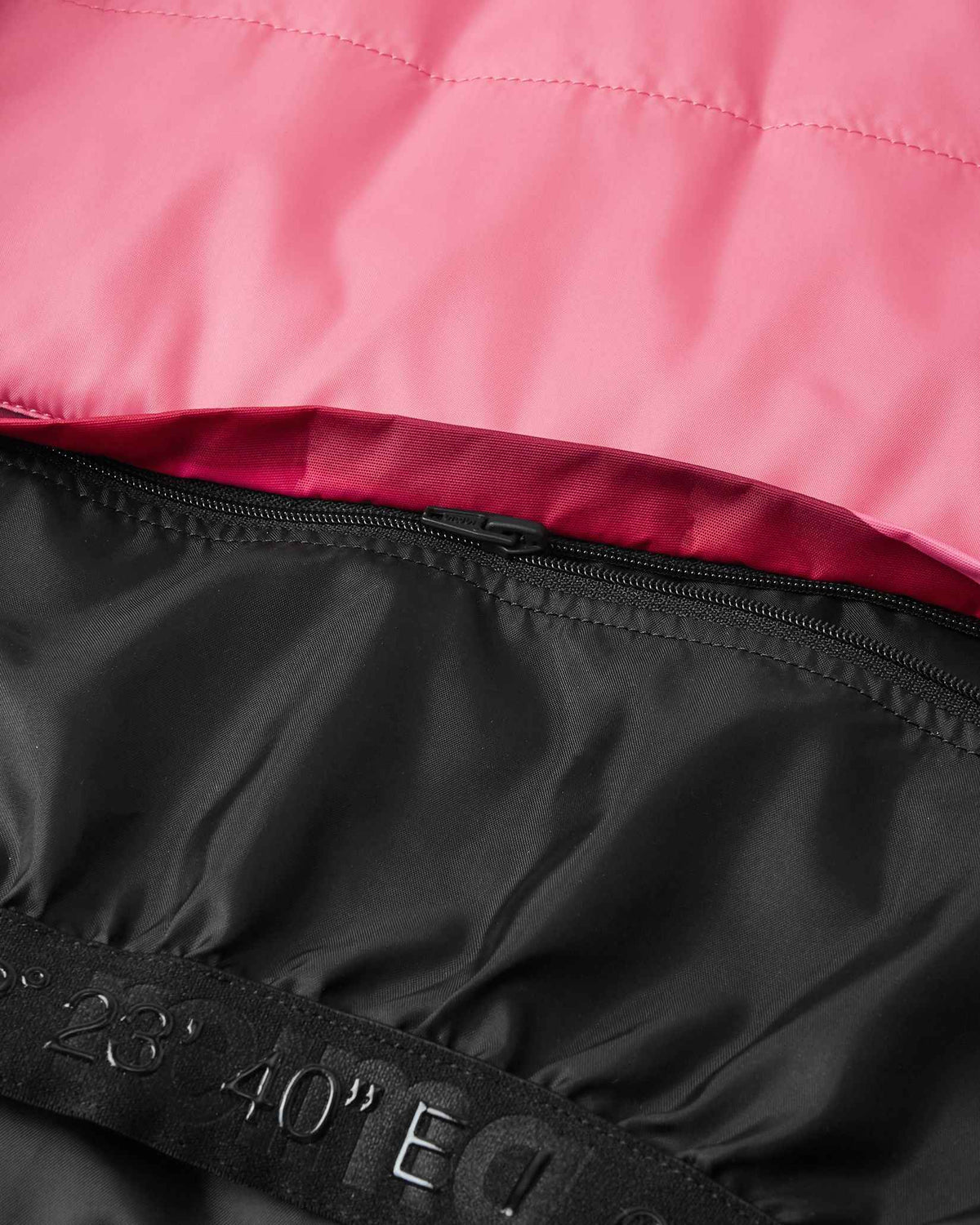 Close-up of the durable zip-in snow skirt attachment on the inside lining of the soft coral Reima Kiiruna kids' winter jacket, engineered to prevent powder snow from riding up during alpine skiing.