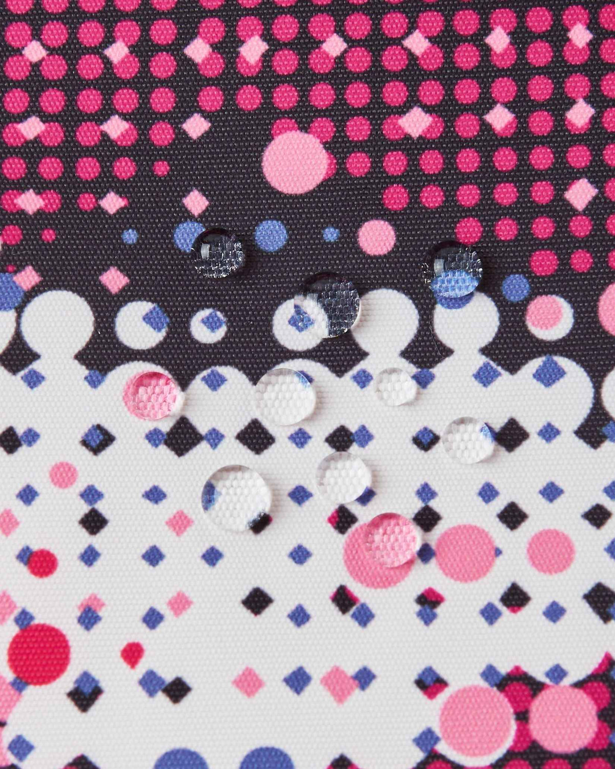 Macro close-up of water droplets beading on the rosy berry dot pattern fabric of the Reima Kiiruna ski jacket, illustrating the fluorocarbon-free BIONIC-FINISH ECO waterproof and dirt-repellent shell.