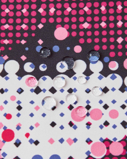 Macro close-up of water droplets beading on the rosy berry dot pattern fabric of the Reima Kiiruna ski jacket, illustrating the fluorocarbon-free BIONIC-FINISH ECO waterproof and dirt-repellent shell.