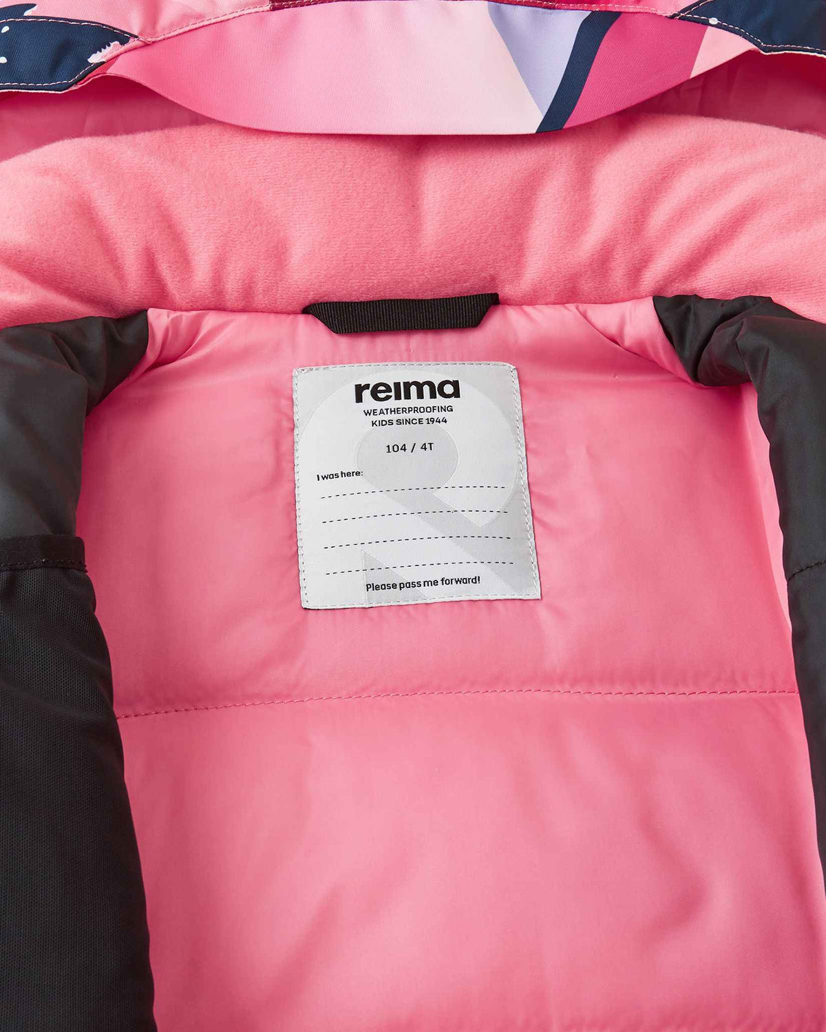 Inside collar view of the soft coral Reima Kiiruna youth ski jacket, displaying the cozy pink fleece lining, Reima weatherproofing certification, and a customizable interior name tag block.