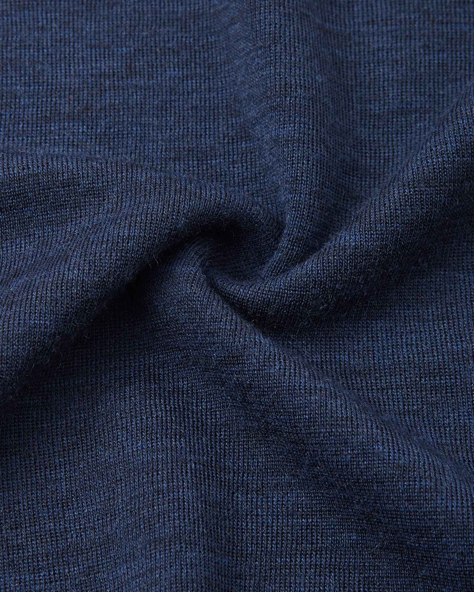 Detailed macro close-up of the navy blue knitted merino wool fabric used in the Reima Kinsei kids base layer set, swirled to display its soft texture.