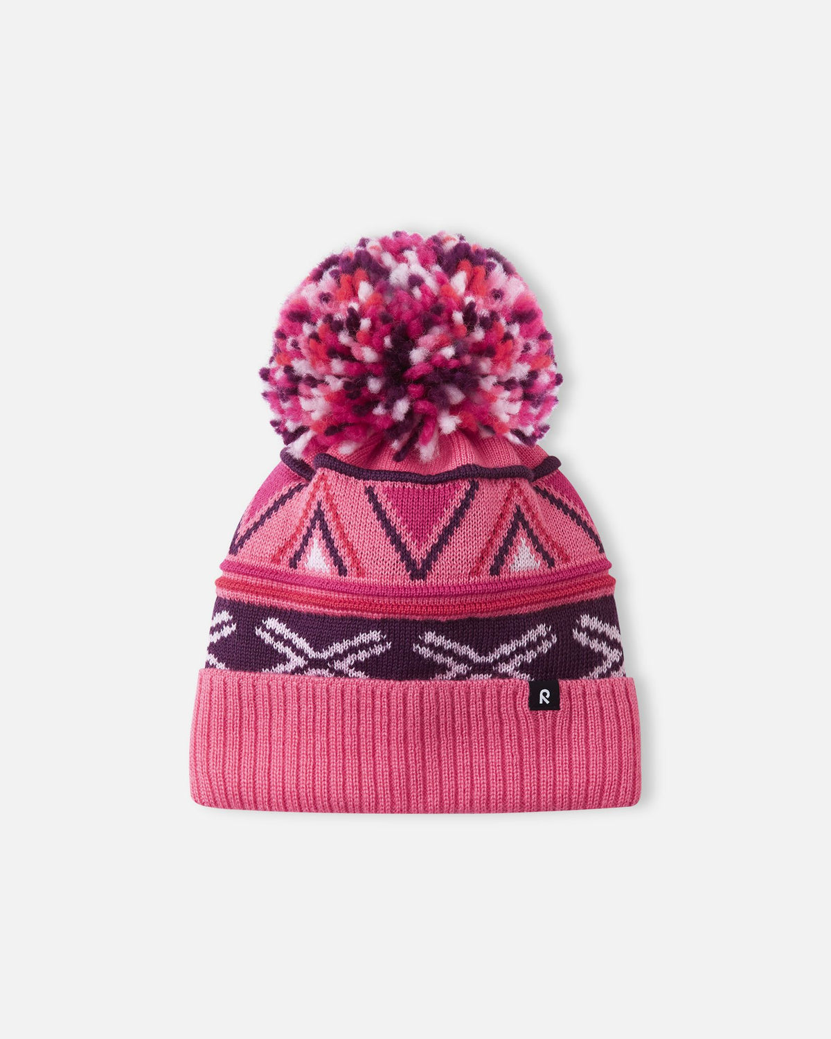 Alternate front flat lay view of the soft coral Reima Kirjoen children's jacquard knit winter hat. The image showcases the premium merino wool-blend texture, the small woven black Reima logo tag on the hem, and the fun geometric winter design.