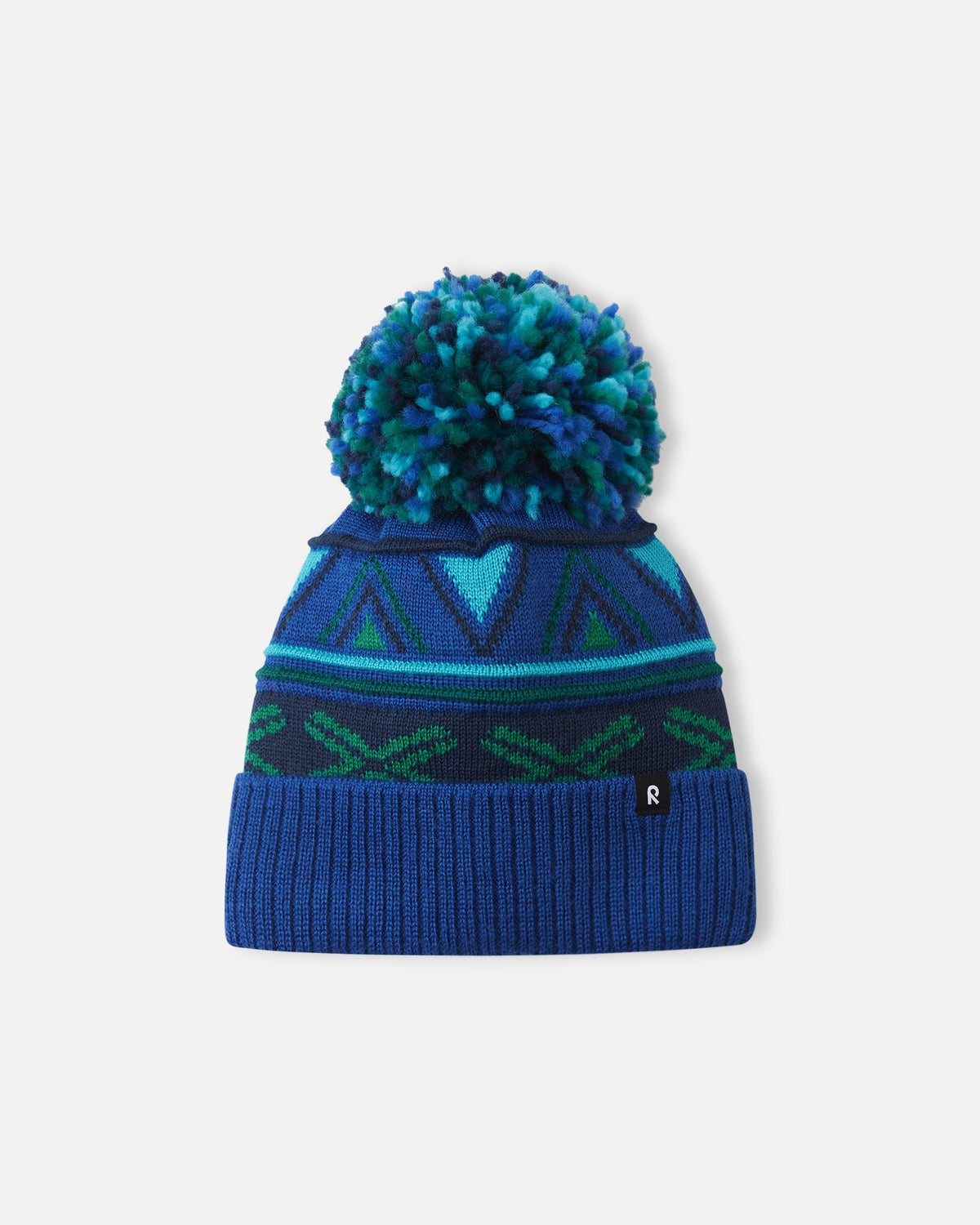 Alternate front flat lay view of the twilight blue Reima Kirjoen children's jacquard knit winter hat. The image showcases the premium merino wool-blend texture, the small woven black Reima logo tag on the hem, and the fun geometric winter design.