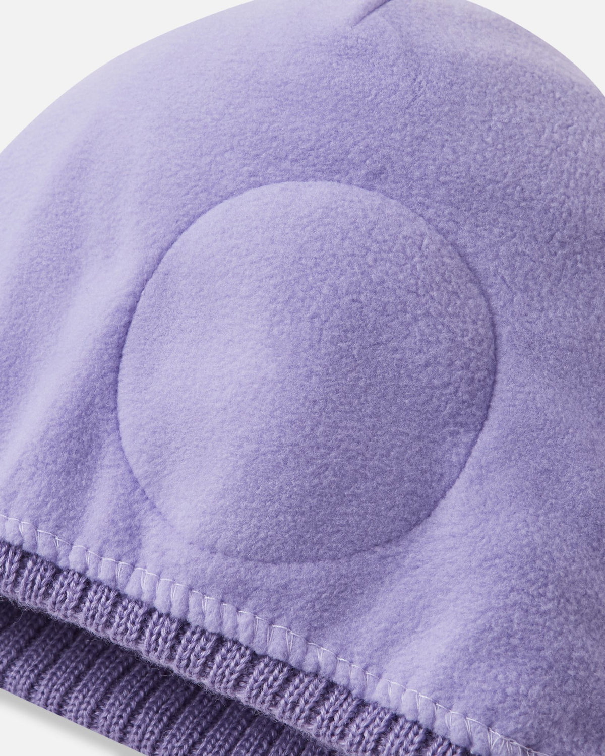 Detailed interior view of the blooming lilac Reima Kirjoen kids' winter beanie. The image reveals the fully lined, soft thermal fleece interior and the specialized circular windproof earpiece inserts engineered to protect children's ears from cold winter winds.
