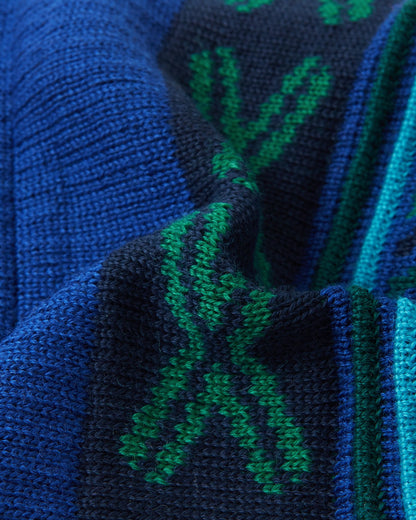 Macro close-up of the thick, colorful geometric jacquard knit structure on the twilight blue Reima Kirjoen kids' winter hat, demonstrating the high-quality texture and flexibility of the warm merino wool-blend yarn.