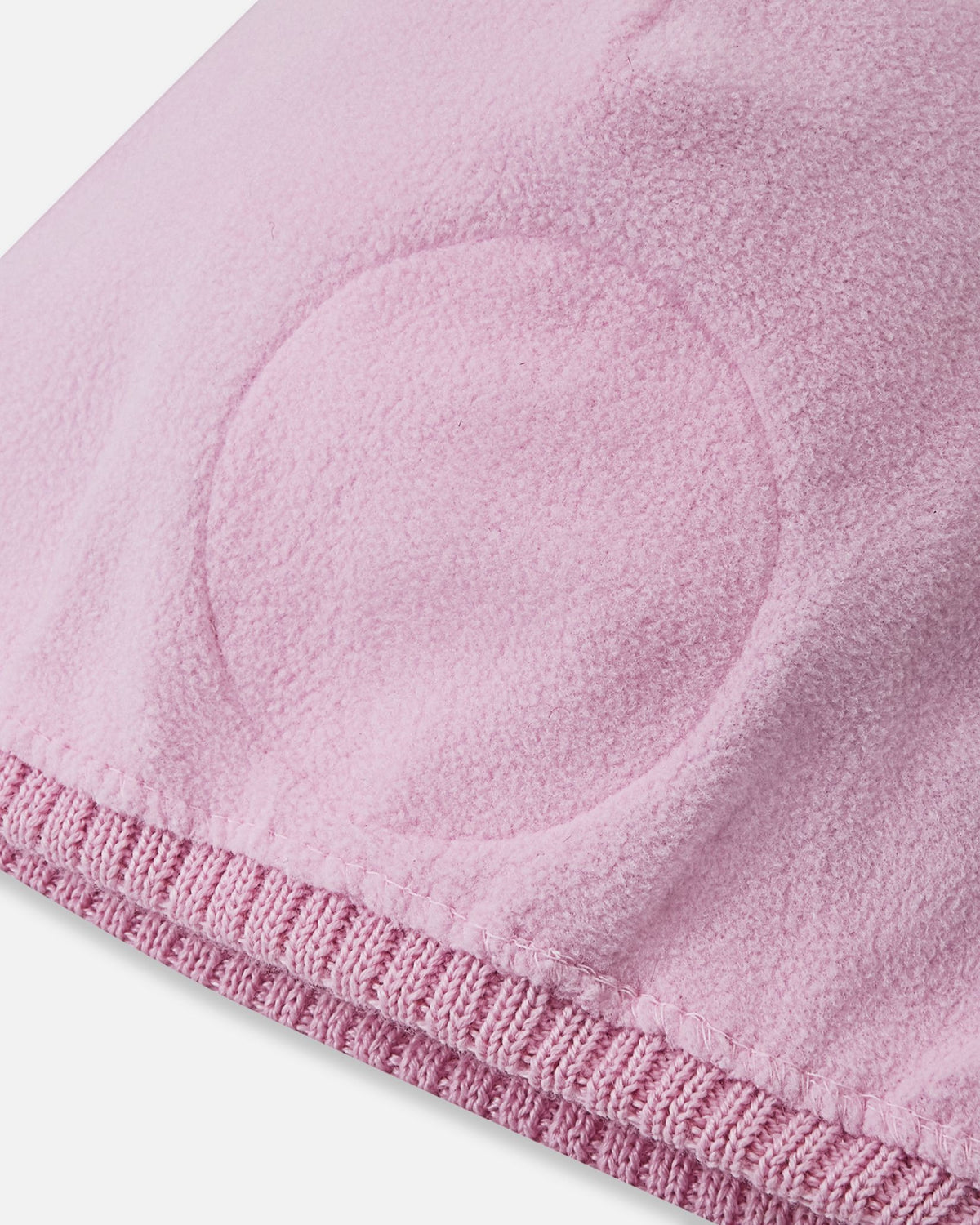 Interior close-up of the Reima Kirjoen kids' merino winter hat, showing the soft pink fleece lining and integrated circular windproof ear barriers designed to block cold drafts.