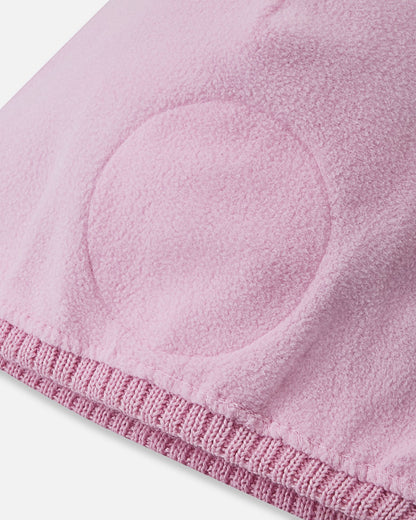 Interior close-up of the Reima Kirjoen kids' merino winter hat, showing the soft pink fleece lining and integrated circular windproof ear barriers designed to block cold drafts.