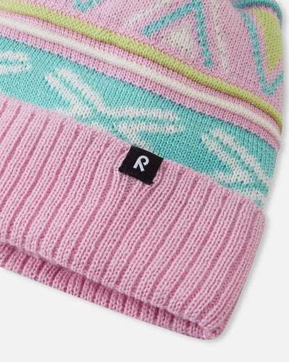 Close-up macro detail of the Reima Kirjoen kids' winter hat, showcasing the fine merino wool jacquard knit in teal and white, ribbed fold-over brim, and woven black Reima logo badge.