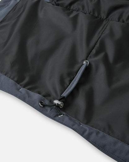 Close-up of the interior bottom hem of the Reima Kuosku kids ski jacket in Soft black, showing the adjustable elastic bungee cord and toggle system to customize the fit and block out wind.