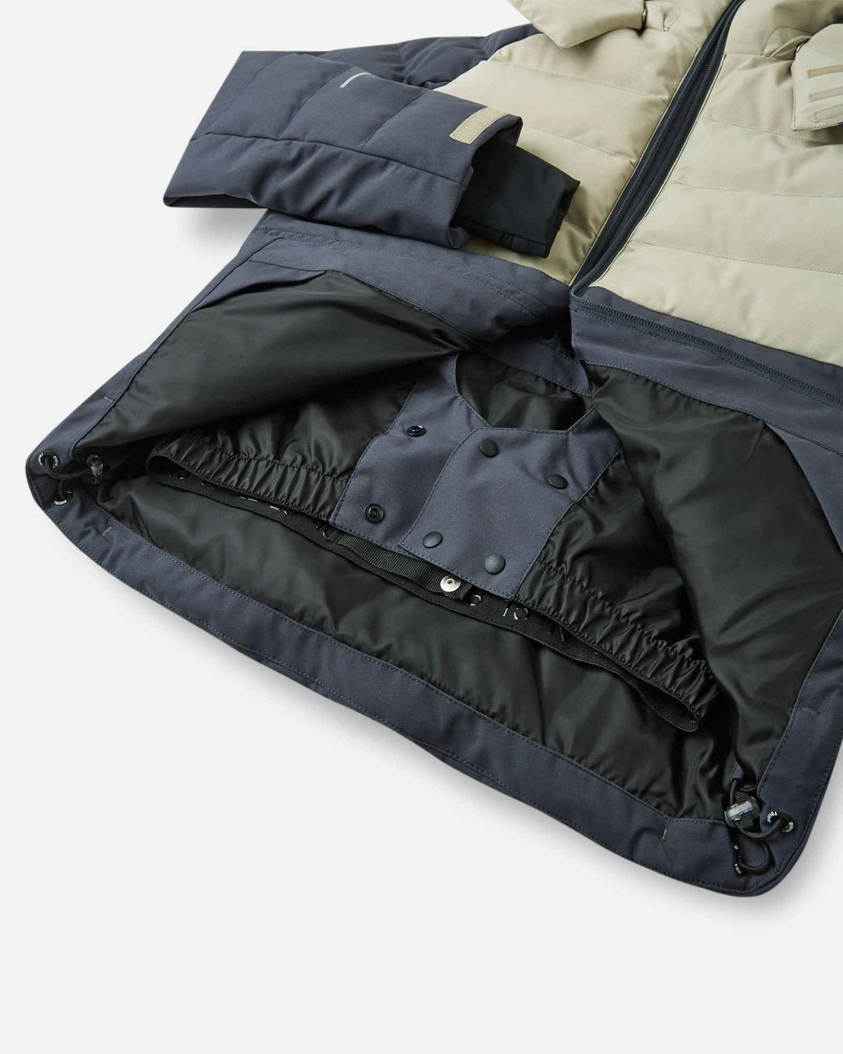 Interior view of the Reima Kuosku kids ski jacket in Soft black, highlighting the built-in snap-button snow skirt designed to keep powder out during winter sports.