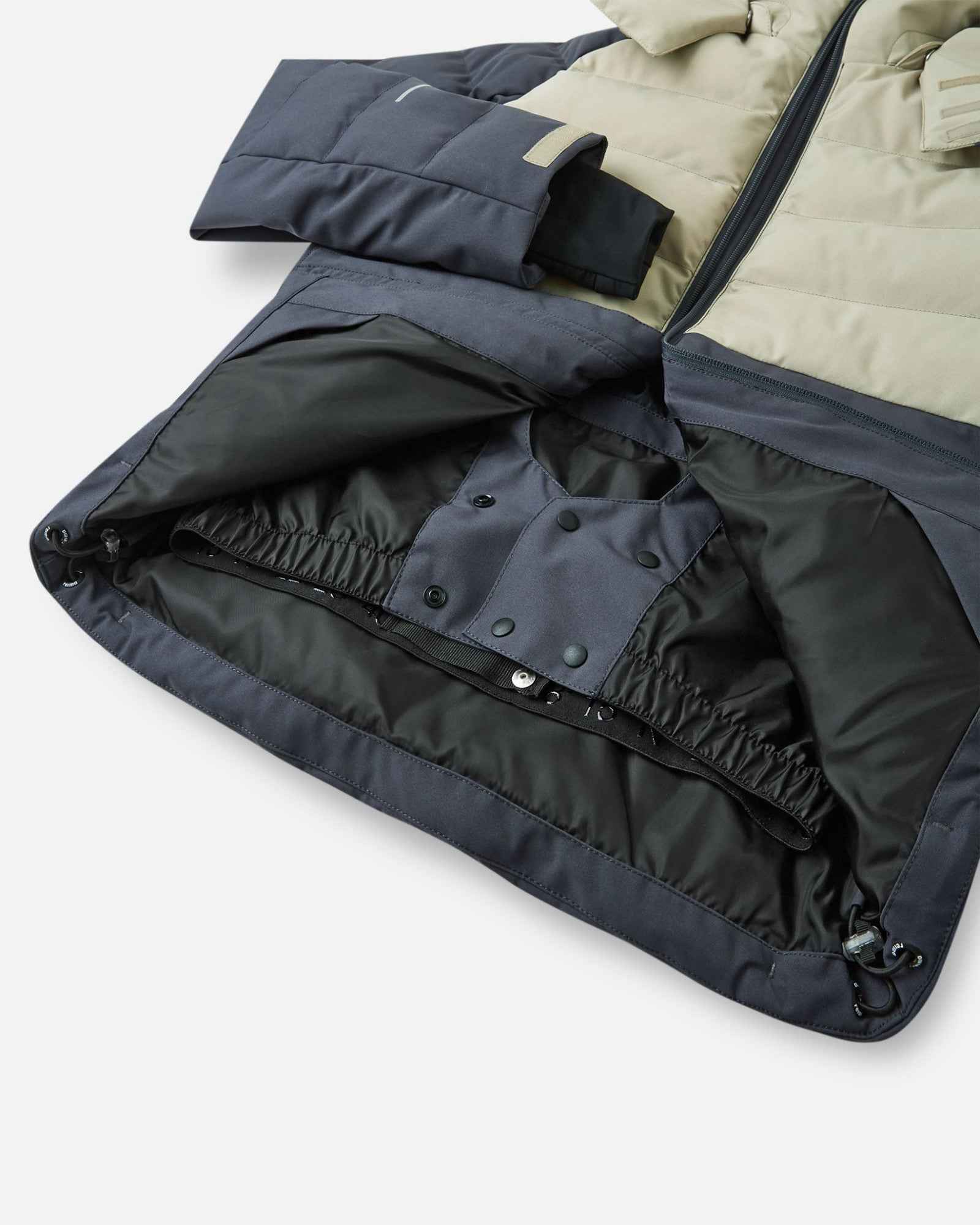 Interior view of the Reima Kuosku kids ski jacket in Soft black, highlighting the built-in snap-button snow skirt designed to keep powder out during winter sports.
