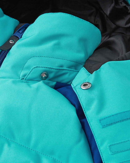 Close-up of the collar area on the Reima Kuosku kids ski jacket in twilight blue, detailing the secure snap buttons used to attach the safe, easily removable winter hood.