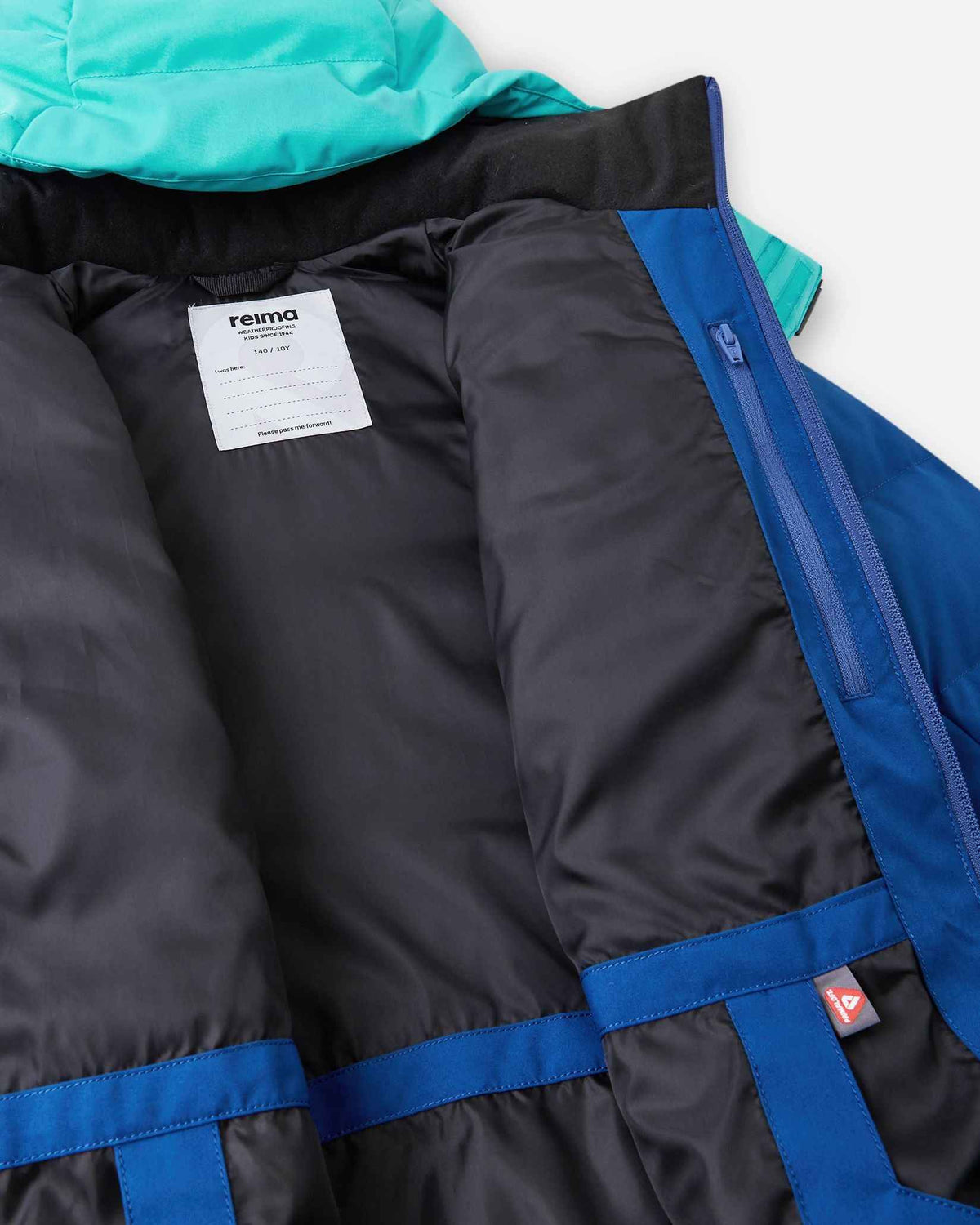 Interior view of the Reima Kuosku kids ski jacket in twilight blue, highlighting the smooth black inner lining, a white Reima brand name tag for personalization, a secure zippered inner chest pocket, and a fleece-lined collar.