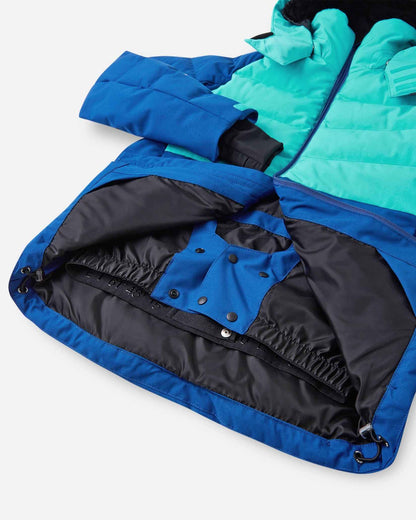 Interior view of the lower half of the Reima Kuosku kids ski jacket in twilight blue, detailing the built-in snow skirt with snap fasteners and an elastic grip band designed to block out snow and cold drafts during winter sports.