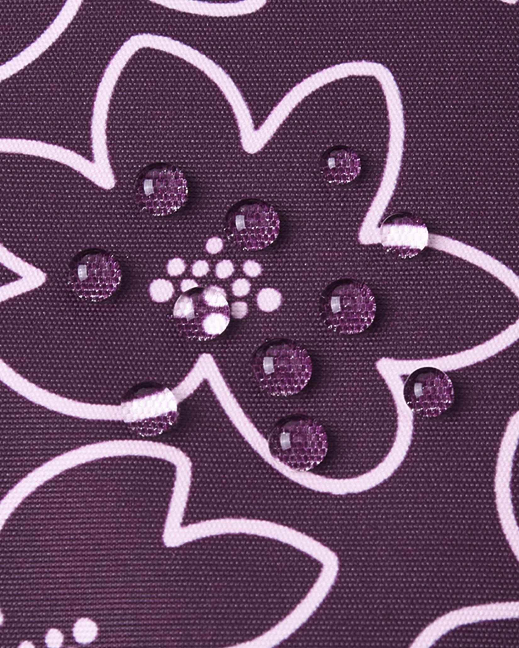 Macro photography of water droplets perfectly beading on the deep purple floral fabric of the Reima Kurikka snowsuit, illustrating the advanced dirt-repellent and waterproof textile technology.