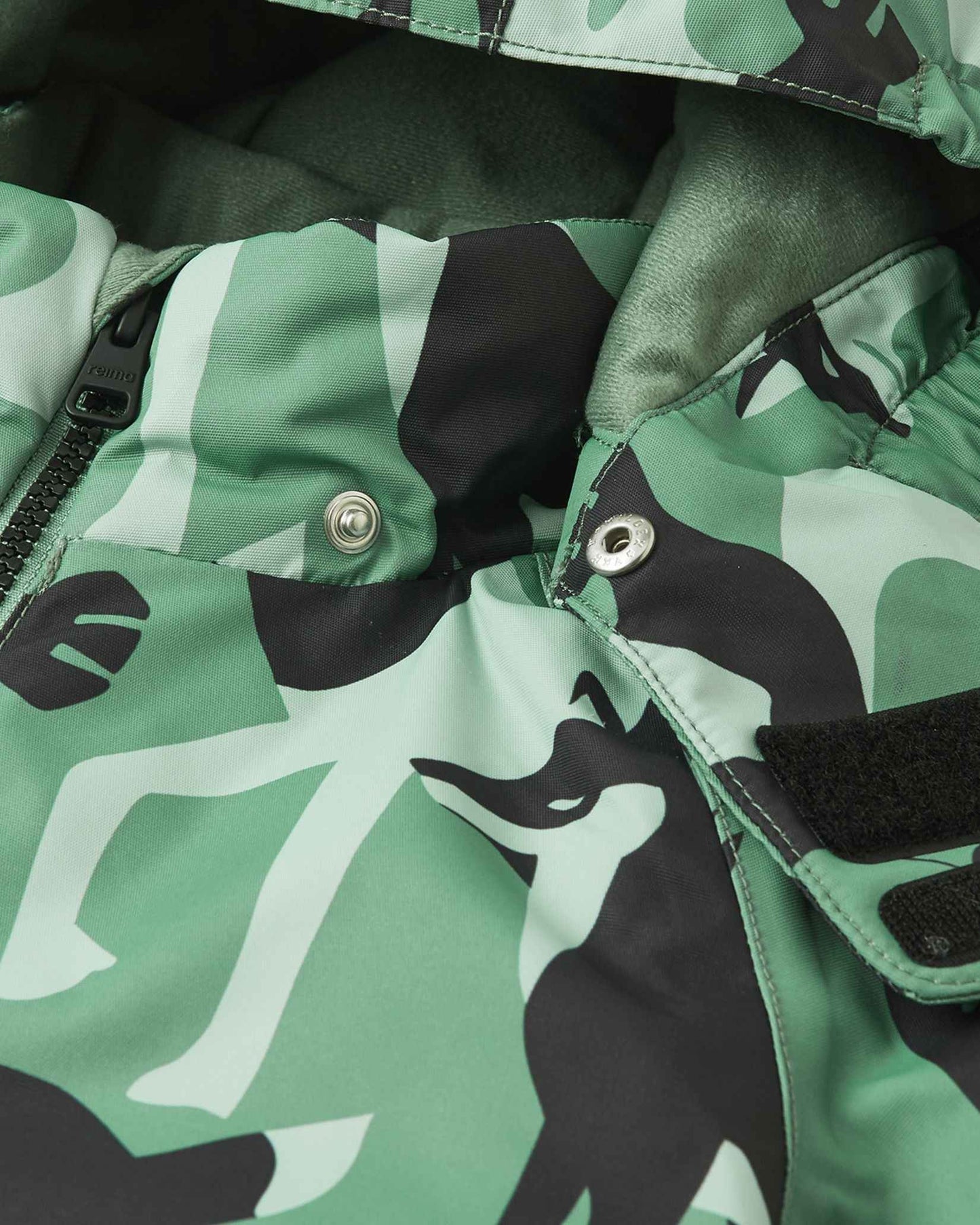 Detailed view of the Reima Kurikka snowsuit collar, showing the safe detachable hood snap buttons and soft interior fleece lining.