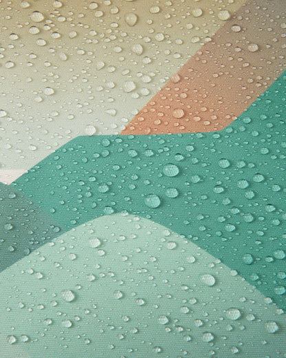 Macro detail of the Reimatec fabric on the Reima Kurikka kids' snowsuit in stone green, showing tight water droplets beading on the surface to demonstrate its waterproof finish.