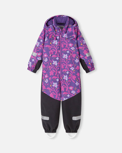 Front view of the Reima Kurikka waterproof kids' snowsuit in plum purple, featuring a bright floral pattern on the top half and durable, solid black reinforced fabric from the waist down to protect against winter wear.
