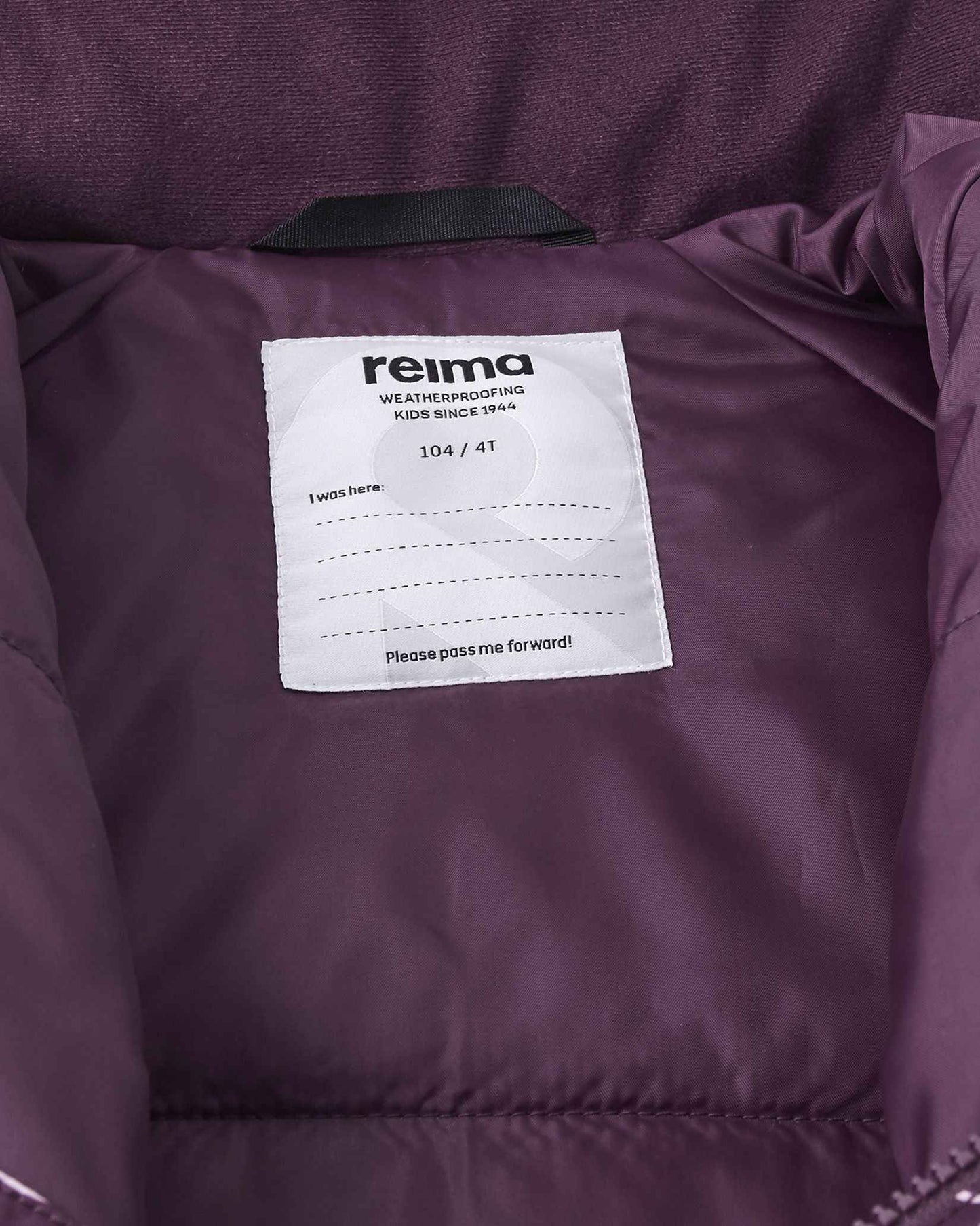 Interior view of the Reima Kurikka snowsuit showcasing the size 104 or 4T label, Reima weatherproofing certification, and a dedicated blank name tag for easy identification at daycare or ski school.