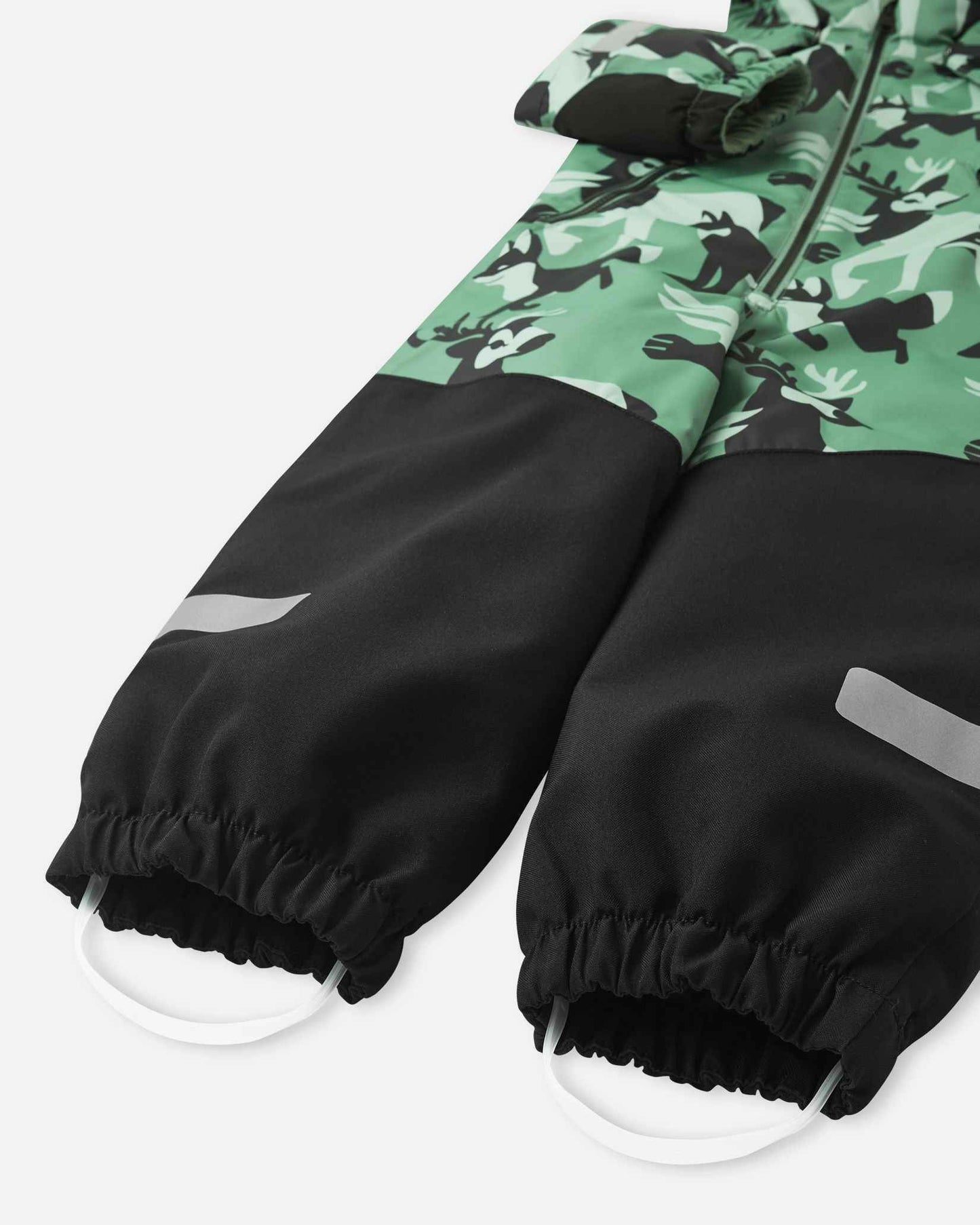Bottom half of the Reima Kurikka snowsuit showing heavy-duty black reinforced leg cuffs, silicone foot loops, and reflective safety bands.