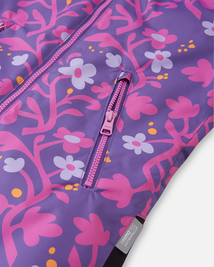 Detail shot of the smooth front zipper and a secure zippered side pocket on the Reima Kurikka snowsuit, set against the vibrant plum purple floral Reimatec fabric.